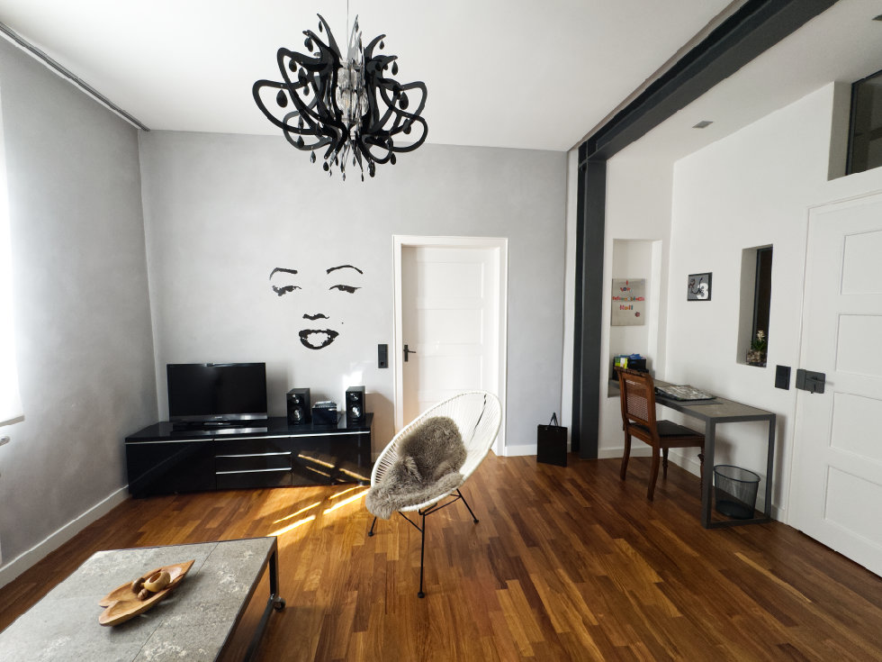 Wohnzimmer mit Blick auf Fernseherboard und rechts kleiner Tisch mit Stuhl.