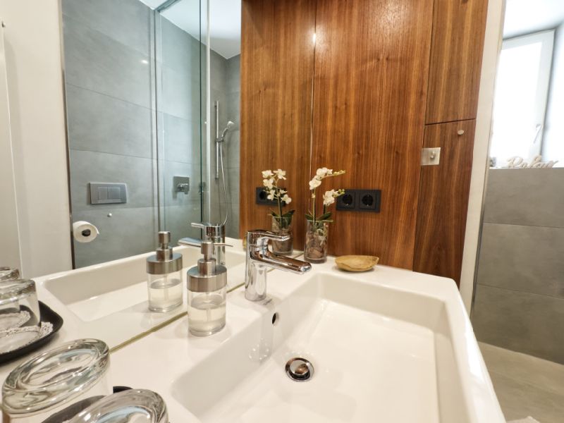 Hochwertiges Badezimmer der Ferienwohnung mit modernem Waschbecken, großer Spiegelfläche und eleganten Holzelementen.