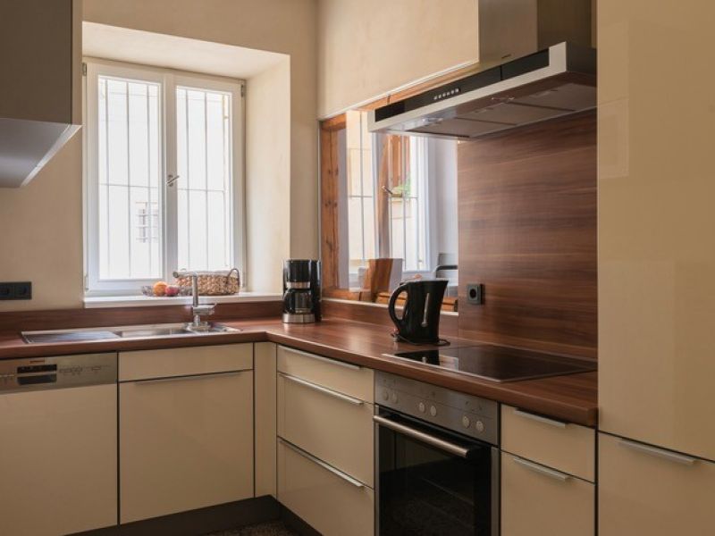 Moderne Küche der Ferienwohnung mit Holzoptik, Einbaugeräten, großem Fenster und kompletter Ausstattung für Selbstversorger.