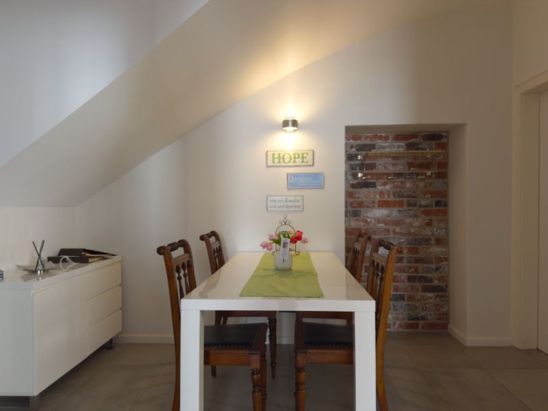 Gemütlicher Essbereich der Ferienwohnung mit großem Tisch, Dachschräge und liebevoller Dekoration im modernen Altstadtstil.